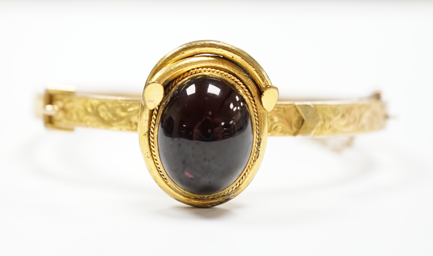 A late Victorian 9ct gold and single stone cabochon red paste set hinged bangle, gross weight 14.5 grams, (adapted?).